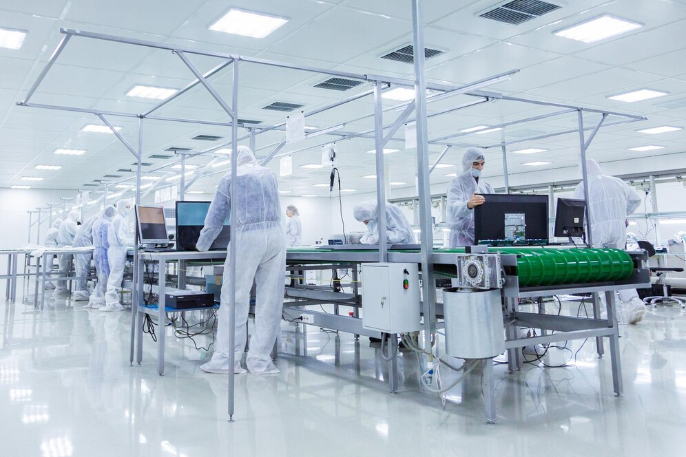 Workers in white protective suits operating machinery inside a factory environment